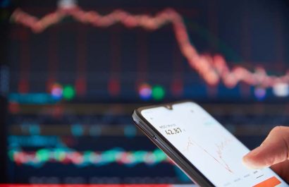 Investor analyzing stock market investments on a smartphone. Person trading stocks on a smartphone. Falling share prices at the stock exchange. Stock market crash. Trader at the stock exchange.
