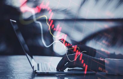 Economy recession and crisis concept with going down digital red financial chart candlestick and graphs on man hands typing on modern laptop outdoors, double exposure