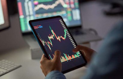 Business man trader broker analyst investor holding tab in hands using digital tablet analyzing stock trade crypto market carts investing finances in stockmarket working in dark night office. Close up