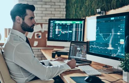 Concentrated young modern man in formalwear working using computers while sitting in the office