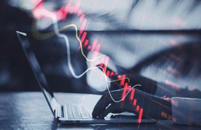 Economy recession and crisis concept with going down digital red financial chart candlestick and graphs on man hands typing on modern laptop outdoors, double exposure