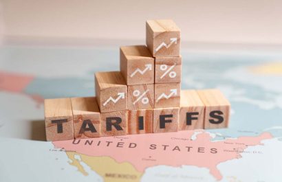 Wooden blocks spelling TARIFFS are placed on a map of North America, specifically over the United States and Mexico. High quality photo