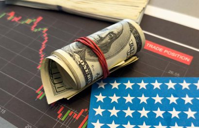 Stock market prices chart. Hundred us dollar bills on the graph. Black and red lines of prices on the chart. American flag under bills.Concept of American finance influence on the market. Macro image