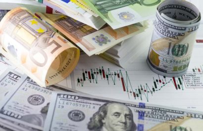 Currency exchange trading. Hundred us dollar bill in foreground. Piles of euro banknotes in background. Currency us eur exchange chart under the bills. fifty euro banknote, hundred dollar bill rolled